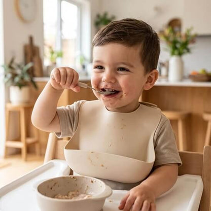 Garçon qui mange de la puréeavec le bavoir bébé beige