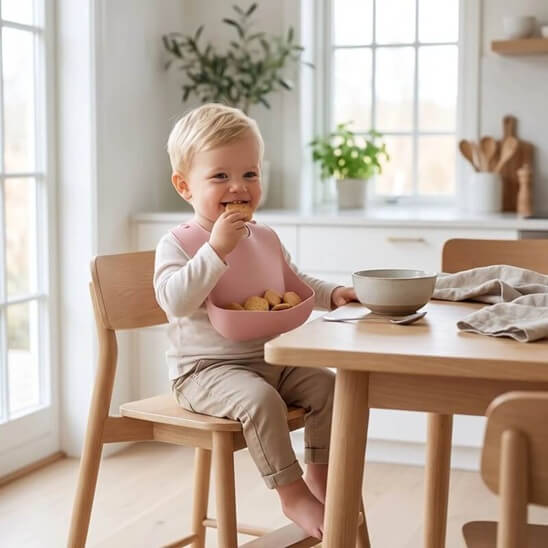 Garçon qui mange des biscuits avec le bavoir bébé rose