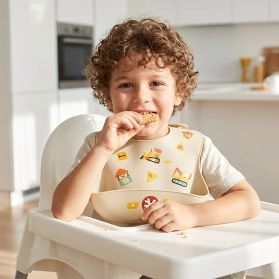 Garçon portant un bavoir bébé ours qui mange un biscuit