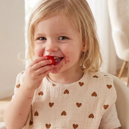 Fillette avec bavoir bébé coeur mangeant des fraises