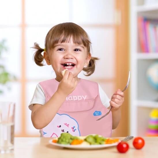 Fillette en train de manger avec le bavoir bébé rose