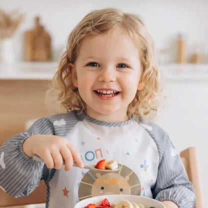 Fillette qui mange des fruits avec bavoir bébé gris lion