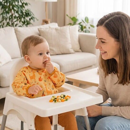 Garçon assis dans le salon avec le bavoir bébé girafe