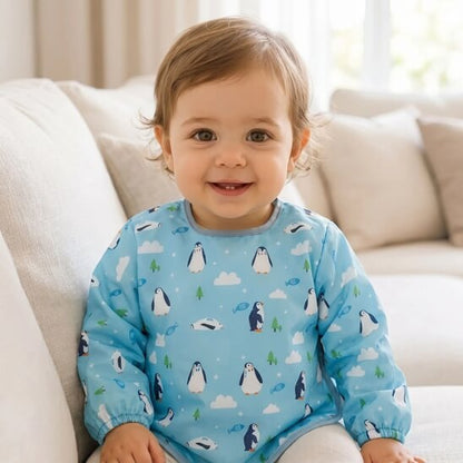Garçon assis dans le salon avec le bavoir bébé pingouin