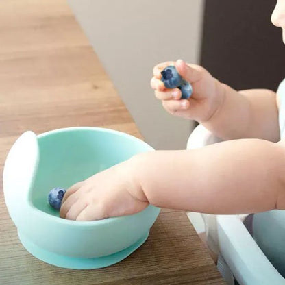 Bébé met ses doigts dans l'assiette bebe verte