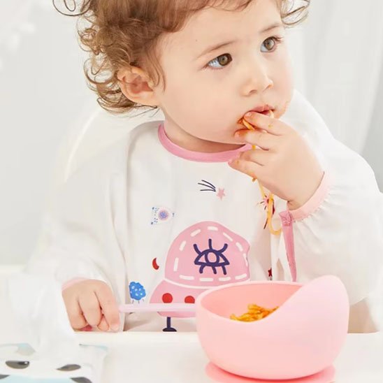 Fillette qui mange avec la cuillère assiette bebe rose