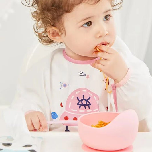 Fillette qui mange avec la cuillère assiette bebe rose