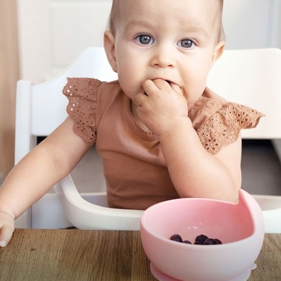 Fillette qui mange avec les doigts assiette bebe rose