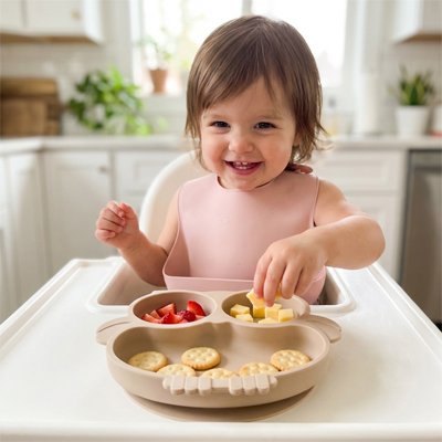 Fillette qui mange avecs ses doigts assiette bébé ventouse beige