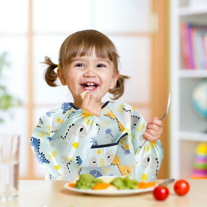 Fillette qui mange des légumes avec bavoir bébé dinosaure