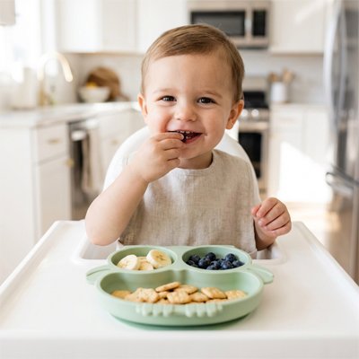 Garçon brun qui mange avec ses doigts assiette bébé ventouse verte