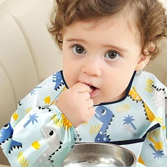 Garçon qui mange avec les doigts avec bavoir bébé dinosaure