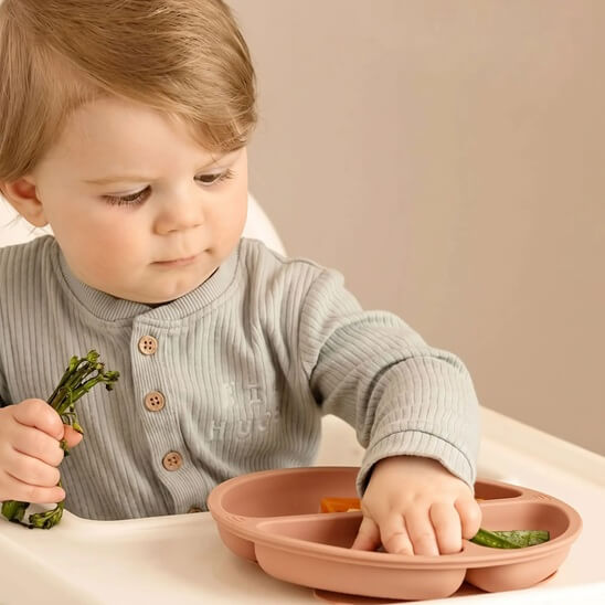 Garçon qui mange avec ses doigts assiette bebe orange